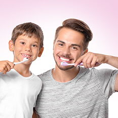 Mały chłopiec i jego ojciec szczotkuje zęby